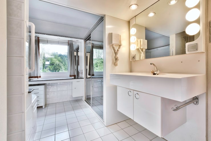 high-end master suite showcasing bath remodeling with light blue custom vanities, white marble floors, gold fixtures, and a freestanding tub in a dedicated wet room.