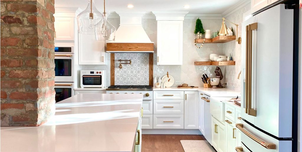 A luxury kitchen remodeling project featuring a large navy blue island with a waterfall countertop, high-vaulted ceilings, and spherical pendant lighting.
