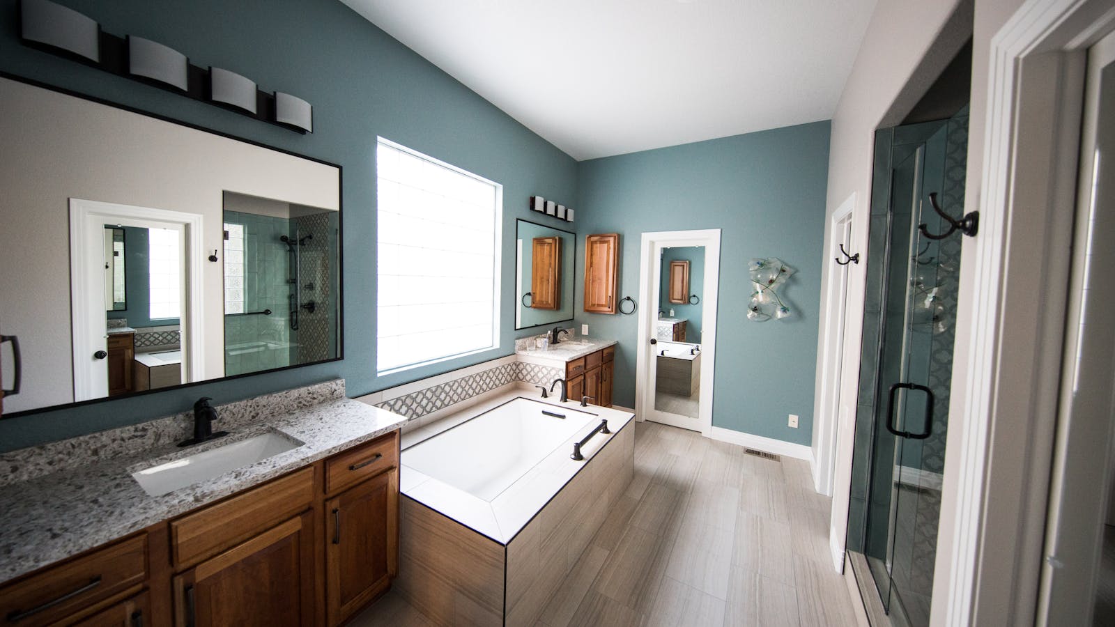 Modern spacious bathroom with freestanding bathtub, wooden cabinets, and granite countertops.