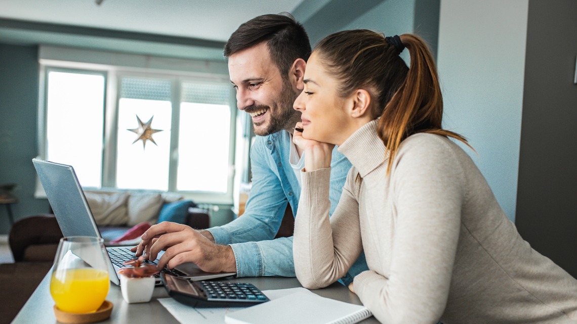 A smiling man and woman looking at a laptop together