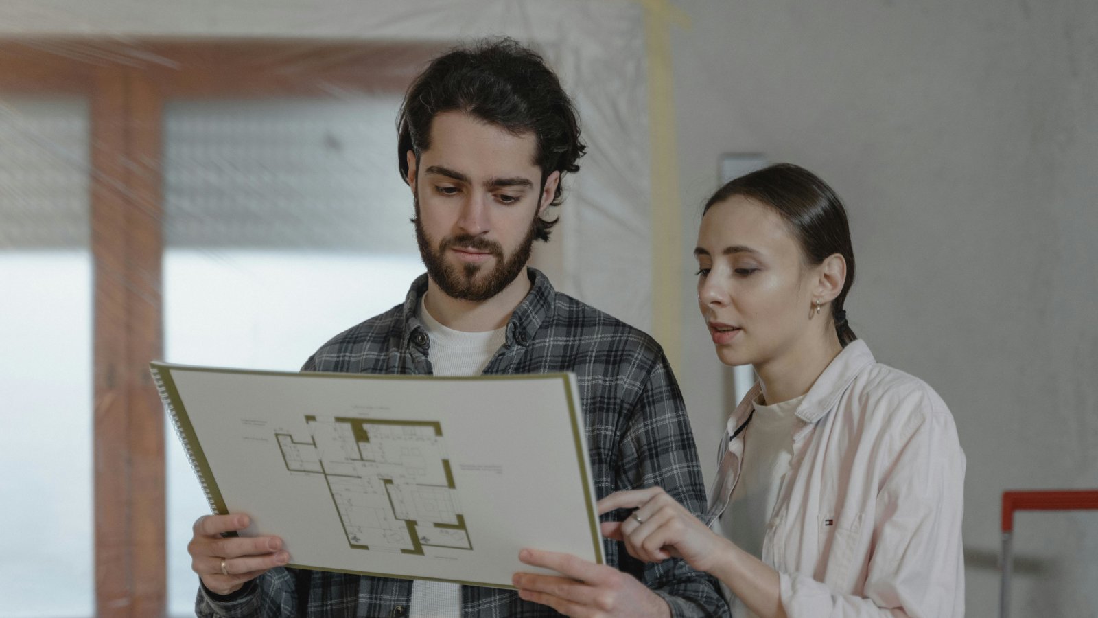 Couple reviewing floor plans indoors for home improvement