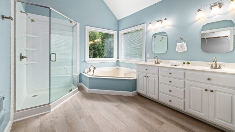 Elegant master bathroom interior featuring a glass shower, bathtub, and dual sink vanity.