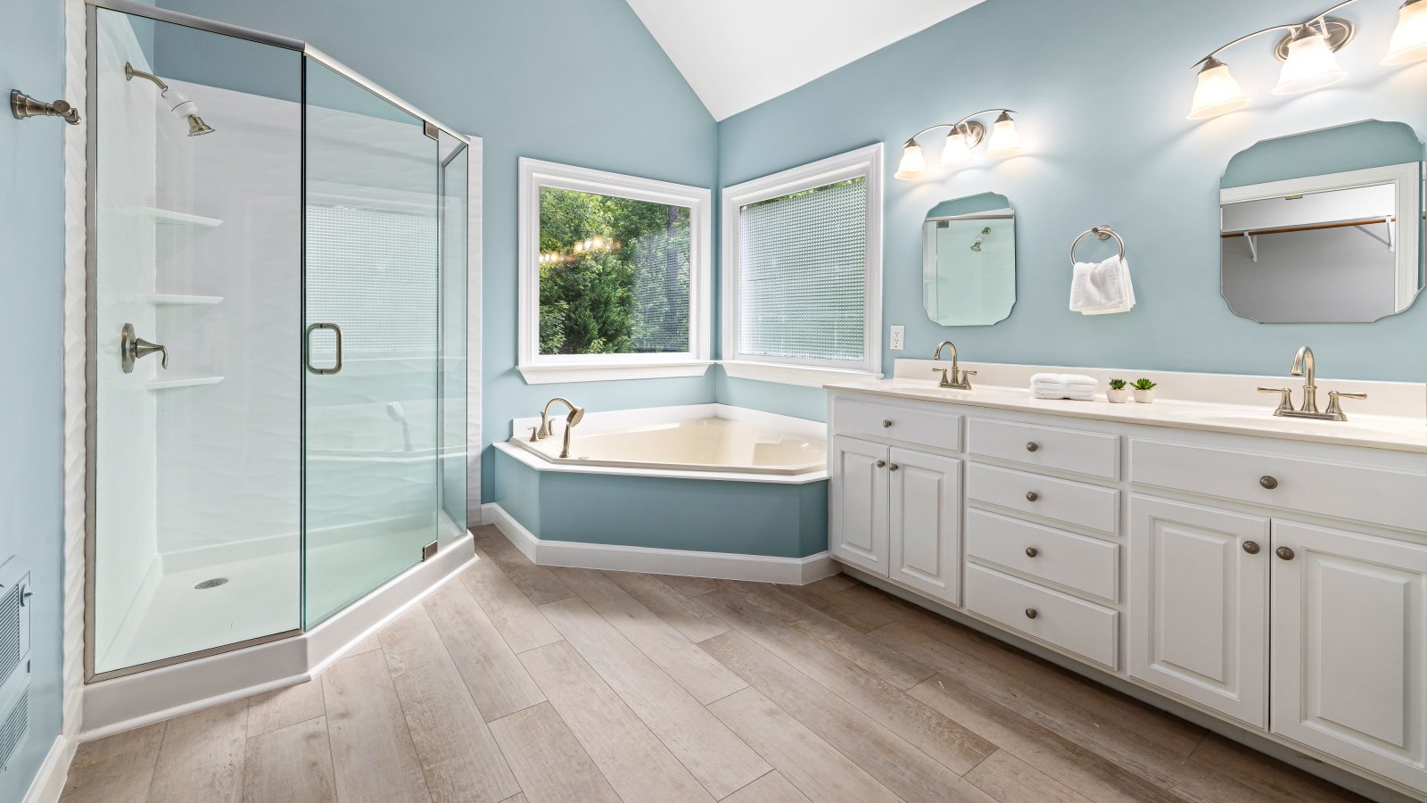 Elegant master bathroom interior featuring a glass shower, bathtub, and dual sink vanity.