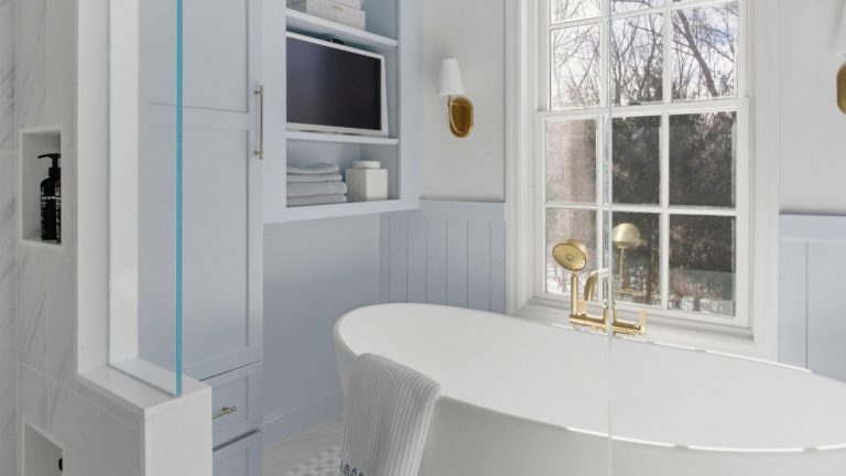 white freestanding bathtub next to light blue cabinetry