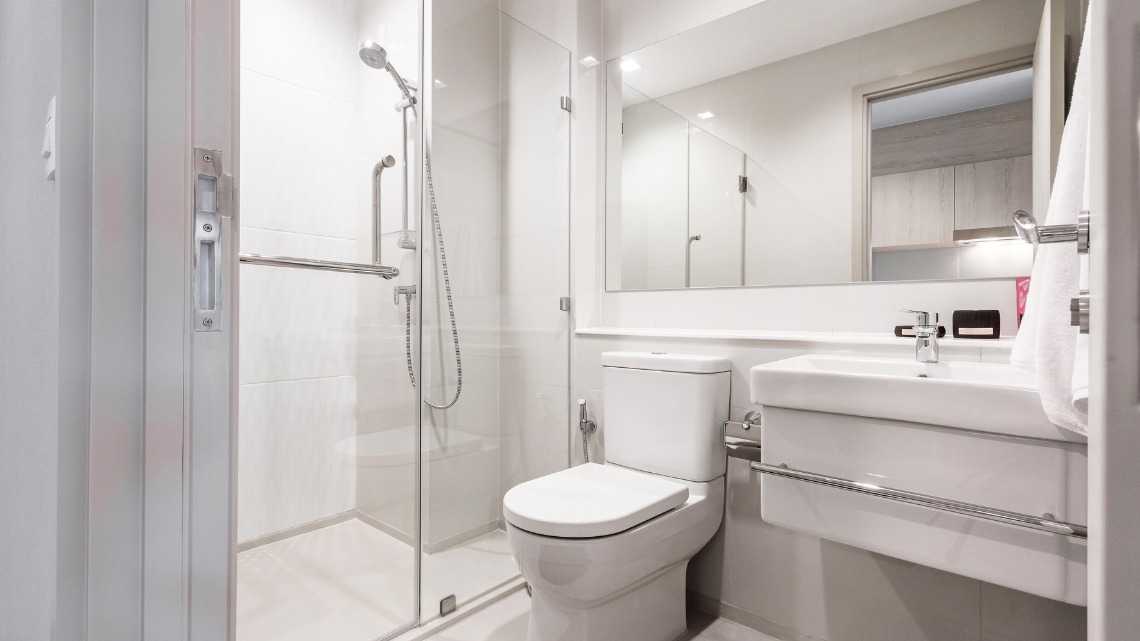 A compact, minimalist white bathroom with a glass-enclosed shower