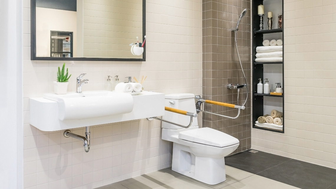 Accessible bathroom featuring a floating sink, a toilet with safety grab bars