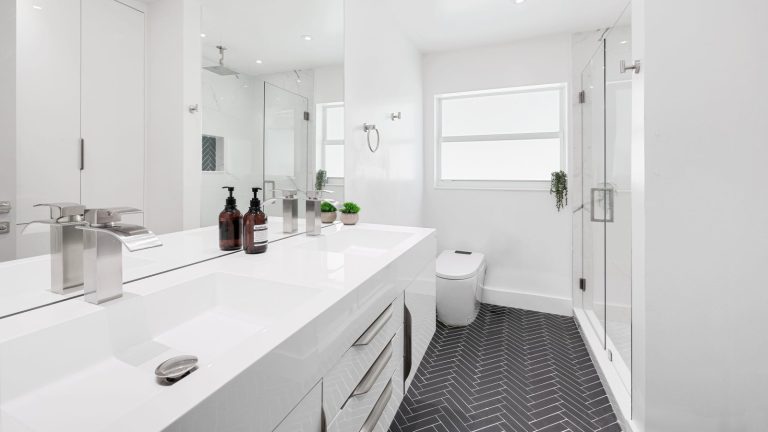 Modern white bathroom featuring sleek fixtures and elegant herringbone flooring design.