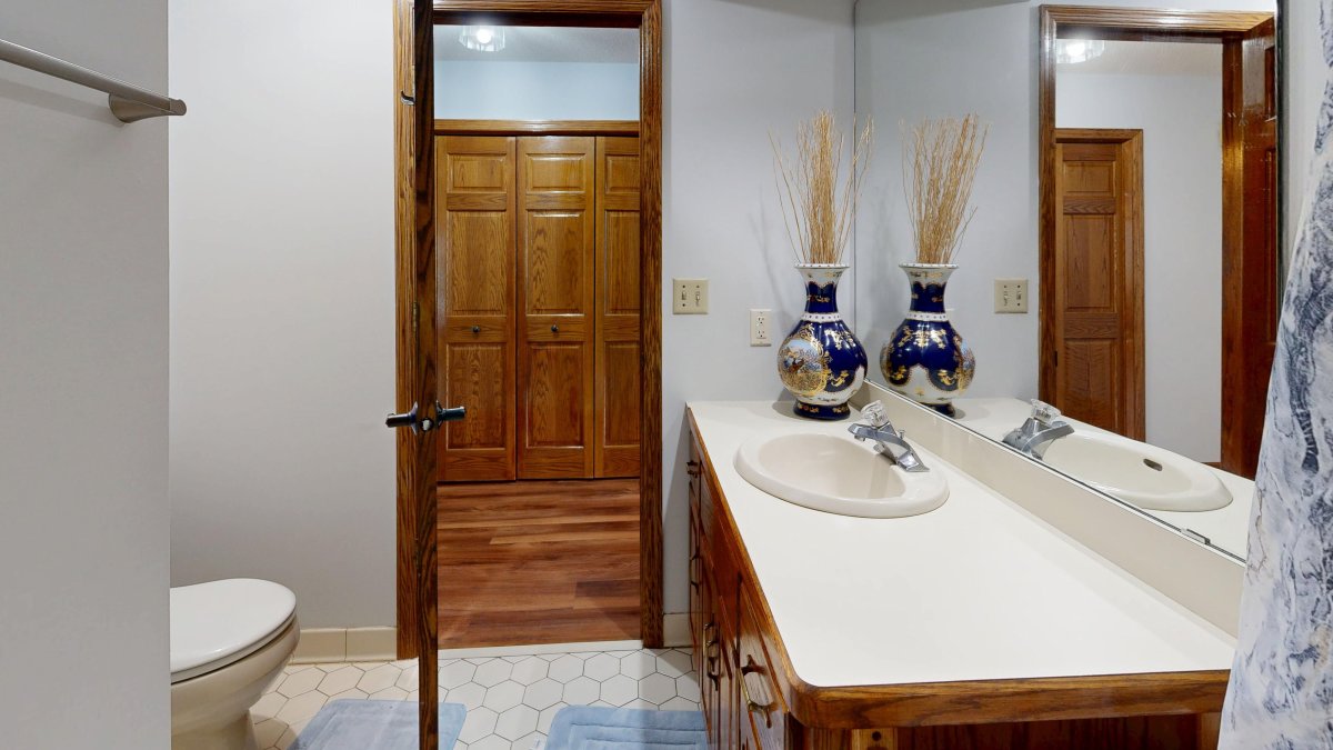 Elegant guest bathroom interior with wooden cabinets and decorative accents for smart storage.