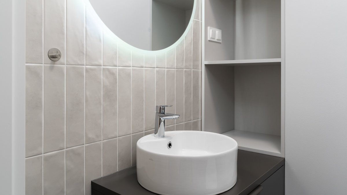 Sleek bathroom vanity with a round mirror and ceramic basin, perfect for compact half bath layouts.